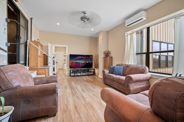 living room with a wall mounted air conditioner, light hardwood / wood-style floors, and ceiling fan