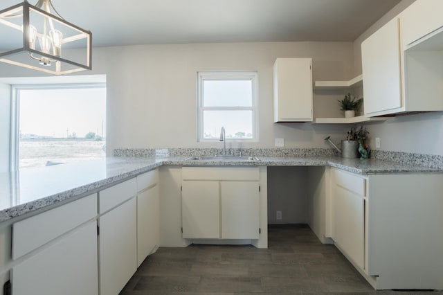 kitchen featuring pendant lighting, sink, light stone counters, and white cabinets