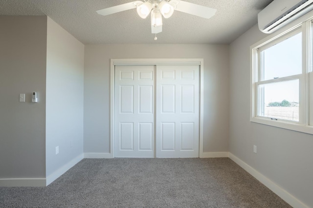 unfurnished bedroom with carpet floors, a wall unit AC, ceiling fan, a textured ceiling, and a closet