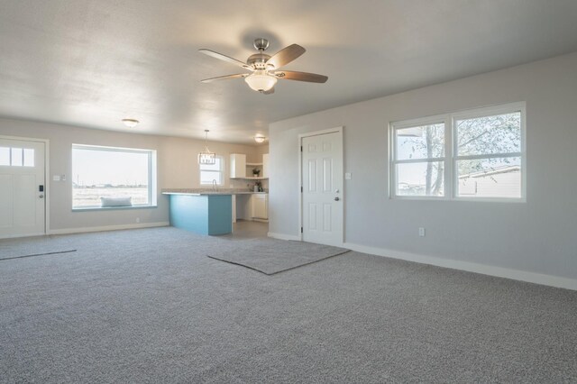 unfurnished living room with ceiling fan with notable chandelier and carpet