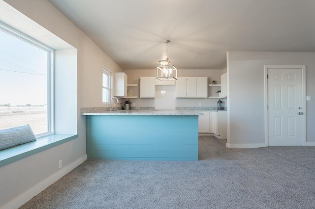 kitchen with white cabinetry, a chandelier, hanging light fixtures, light colored carpet, and kitchen peninsula