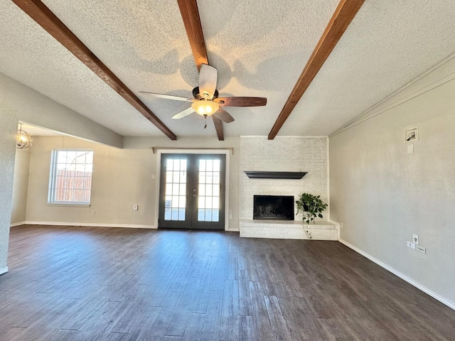 unfurnished living room featuring dark wood-type flooring, ceiling fan, a fireplace, a textured ceiling, and beamed ceiling