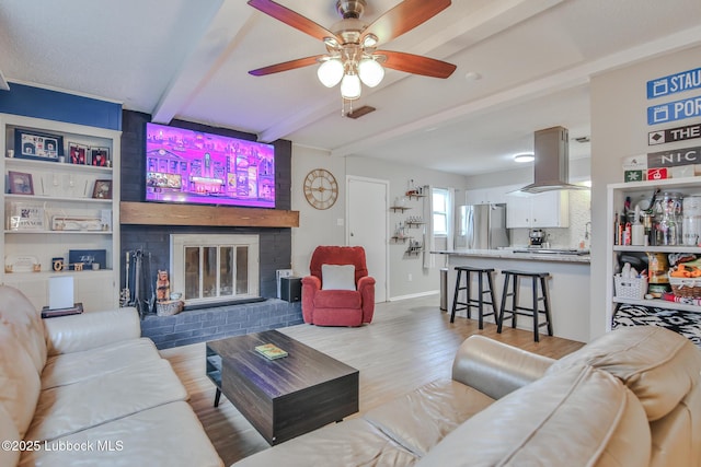 4816 55th St, Lubbock, TX 79414 - living room featuring beam ceiling, wood finished floors, ceiling fan, a fireplace, and baseboards