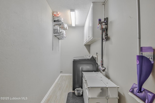 4816 55th St, Lubbock, TX 79414 - washroom featuring cabinet space, light wood-style floors, washing machine and clothes dryer, a textured ceiling, and baseboards