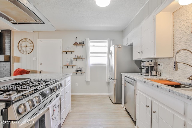 4816 55th St, Lubbock, TX 79414 - kitchen with stainless steel appliances, a sink, light wood finished floors, a textured ceiling, and white cabinets
