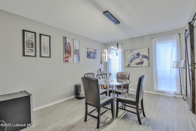 4816 55th St, Lubbock, TX 79414 - dining area featuring light wood-style floors, baseboards, and a textured ceiling