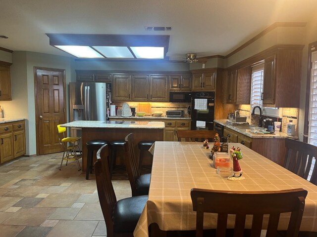 kitchen with a center island, tile counters, ceiling fan, and black appliances