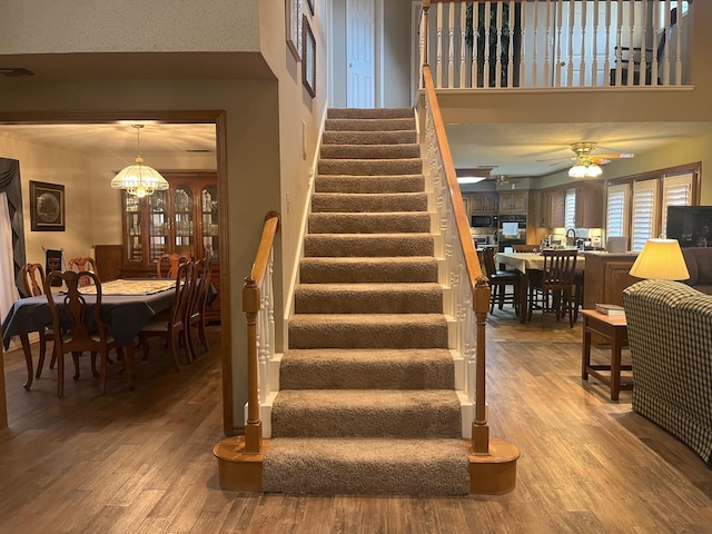 stairway with hardwood / wood-style floors and ceiling fan