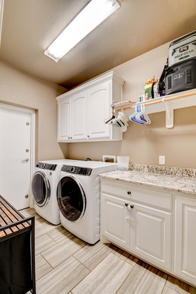 washroom with cabinets, light hardwood / wood-style flooring, washer and dryer, and a textured ceiling