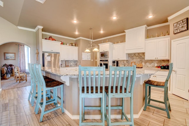 kitchen featuring white cabinetry, stainless steel appliances, and a large island with sink