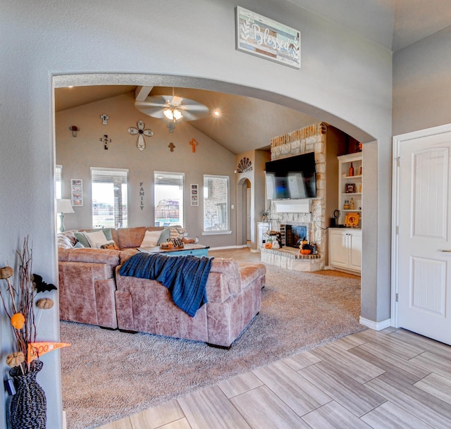 living room with a fireplace, high vaulted ceiling, beamed ceiling, and ceiling fan