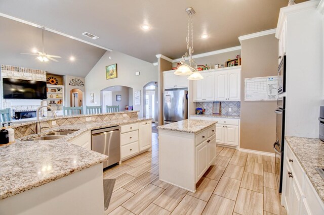 kitchen featuring sink, white cabinetry, a center island, appliances with stainless steel finishes, and light stone countertops