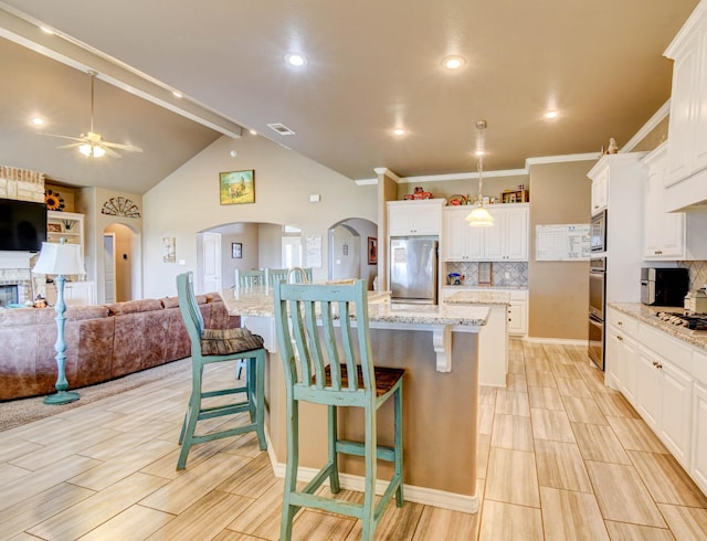 kitchen featuring a kitchen island with sink, a kitchen bar, white cabinets, and appliances with stainless steel finishes