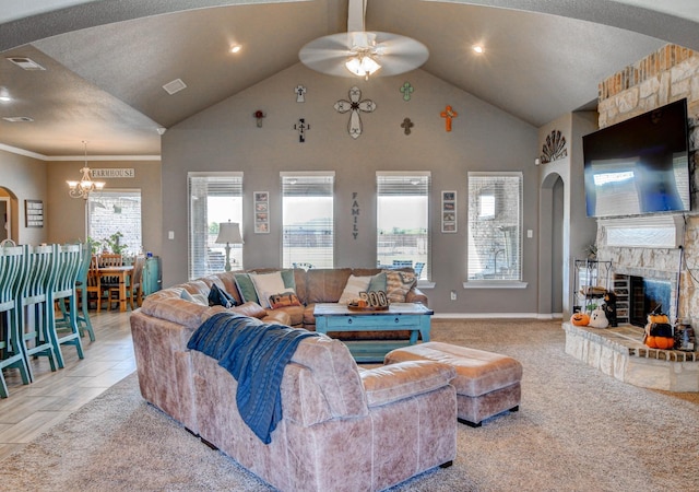 carpeted living room featuring a stone fireplace, ceiling fan with notable chandelier, and high vaulted ceiling