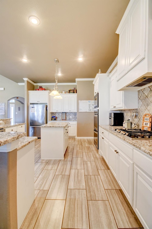 kitchen with appliances with stainless steel finishes, a center island, hanging light fixtures, and white cabinets