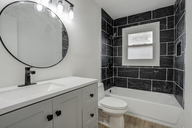 full bathroom featuring tiled shower / bath combo, vanity, hardwood / wood-style floors, and toilet