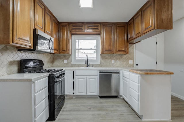 kitchen featuring appliances with stainless steel finishes, sink, light hardwood / wood-style floors, and decorative backsplash