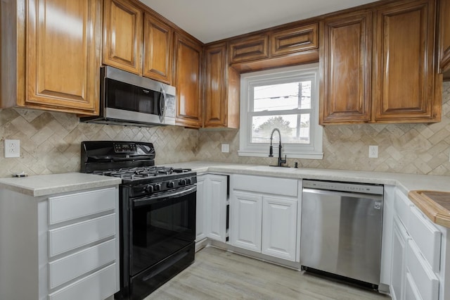 kitchen with sink, appliances with stainless steel finishes, light hardwood / wood-style floors, decorative backsplash, and white cabinets