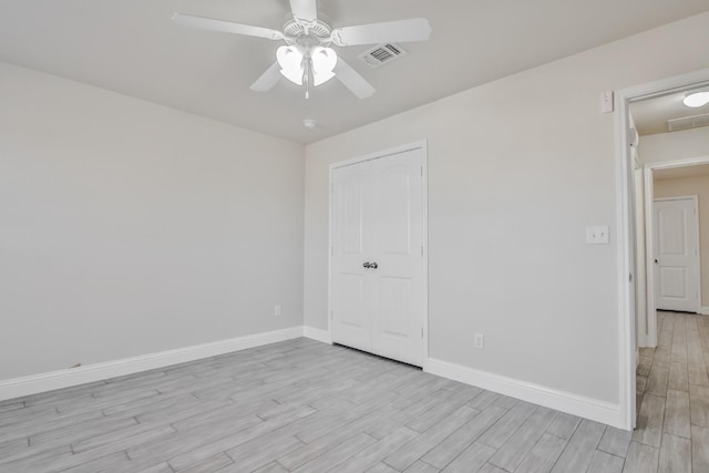 empty room with ceiling fan and light hardwood / wood-style flooring