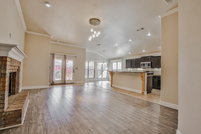 unfurnished living room featuring lofted ceiling, a chandelier, crown molding, a brick fireplace, and light hardwood / wood-style flooring