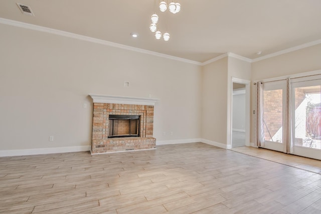 unfurnished living room featuring a notable chandelier, ornamental molding, a fireplace, and light wood-type flooring