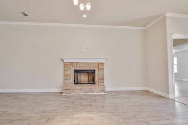 unfurnished living room featuring crown molding, an inviting chandelier, a brick fireplace, and light hardwood / wood-style flooring