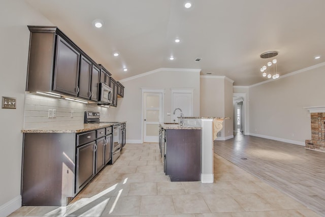 kitchen featuring light stone counters, stainless steel appliances, sink, and dark brown cabinets