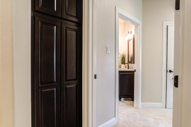 hall with sink and light colored carpet