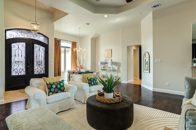 interior space with hardwood / wood-style flooring, ceiling fan with notable chandelier, french doors, and a raised ceiling