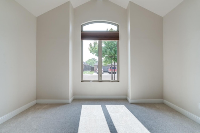 carpeted empty room with lofted ceiling