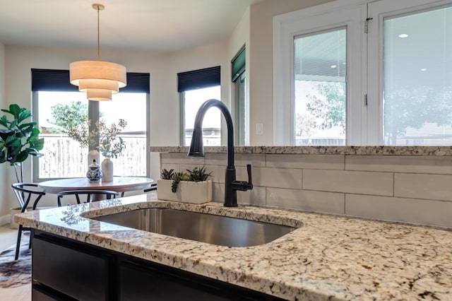 kitchen with sink, decorative light fixtures, and light stone countertops