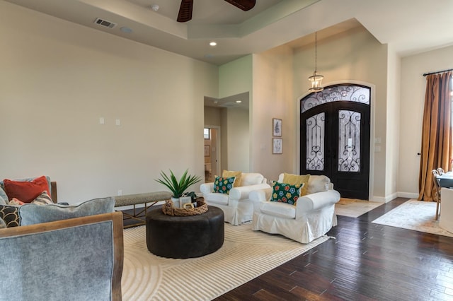 living room with hardwood / wood-style floors, french doors, a raised ceiling, and ceiling fan