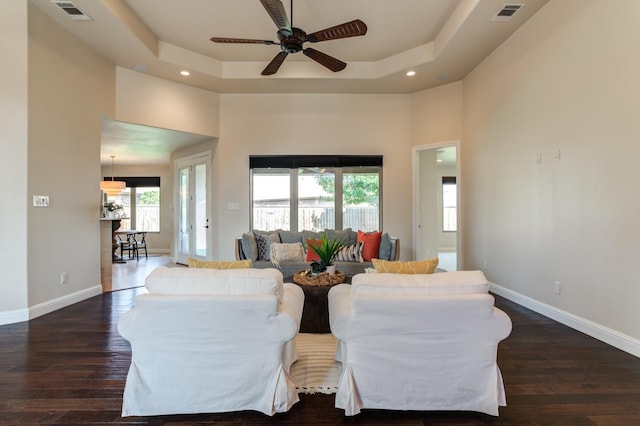 living room featuring dark hardwood / wood-style floors, a tray ceiling, and a high ceiling