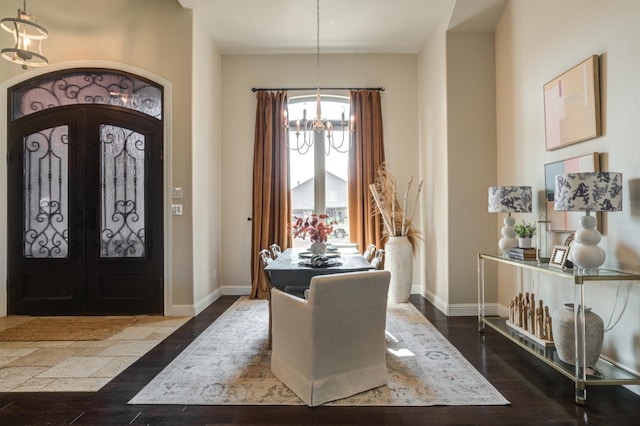 foyer with french doors, a chandelier, and dark wood-type flooring