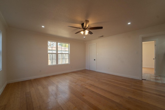 empty room with a textured ceiling, ornamental molding, ceiling fan, and light wood-type flooring