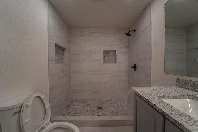 bathroom featuring vanity, toilet, and tiled shower