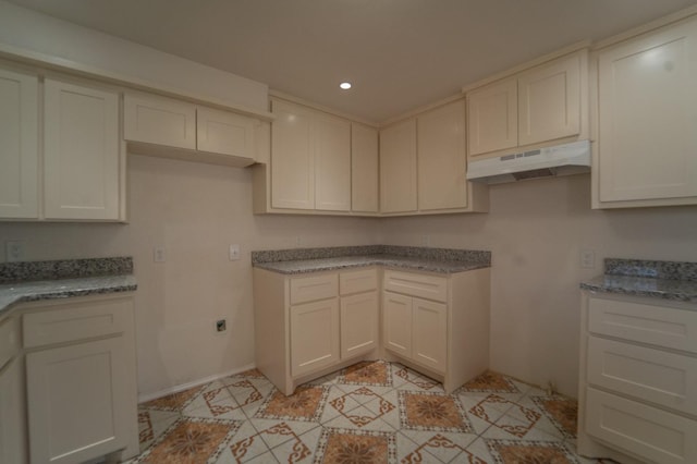 kitchen with white cabinetry and light stone countertops