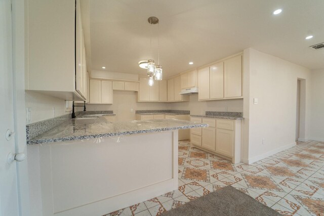 kitchen featuring decorative light fixtures, sink, white cabinets, light stone counters, and kitchen peninsula