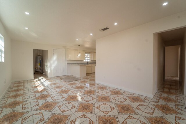 unfurnished living room featuring water heater and light tile patterned flooring