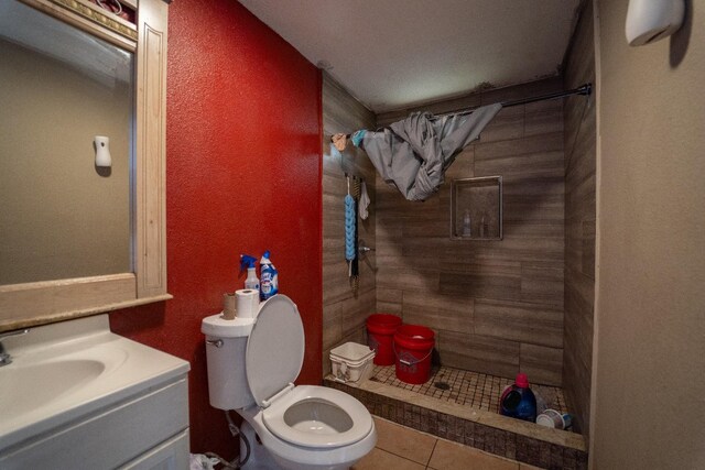 bathroom featuring vanity, toilet, tile patterned flooring, and a tile shower