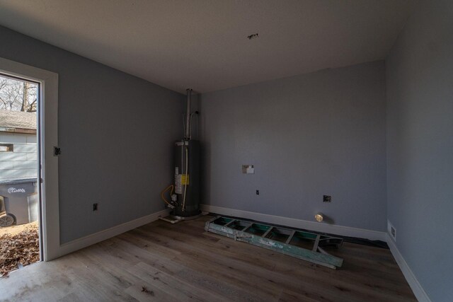 unfurnished room with wood-type flooring and gas water heater