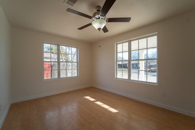 spare room with a wealth of natural light, light hardwood / wood-style floors, and ceiling fan