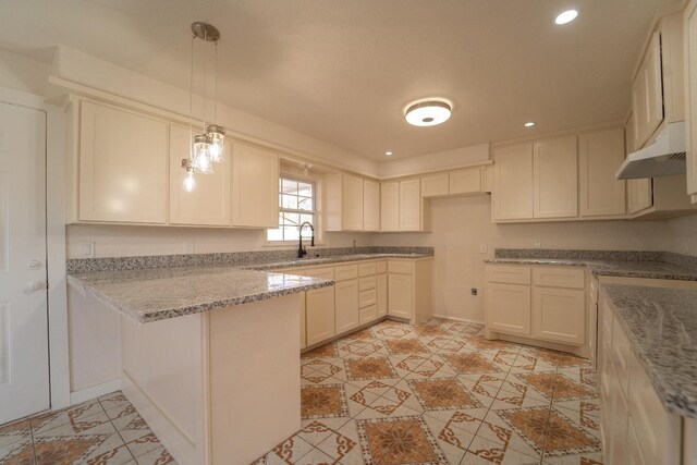 kitchen with pendant lighting, sink, light stone countertops, white cabinets, and kitchen peninsula