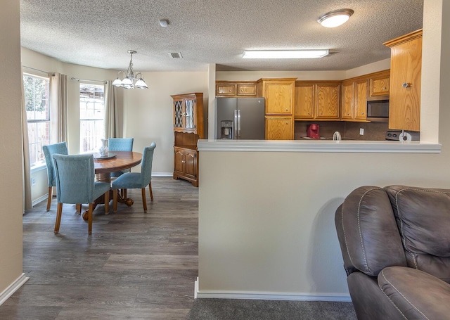 kitchen with appliances with stainless steel finishes, baseboards, and a notable chandelier