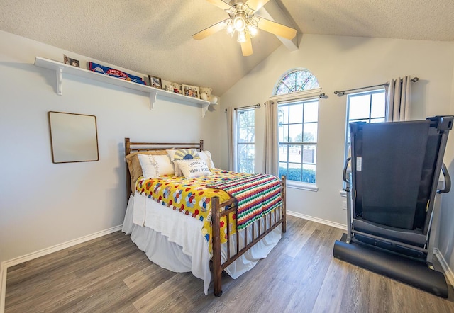 bedroom with lofted ceiling with beams, a textured ceiling, a ceiling fan, baseboards, and wood finished floors