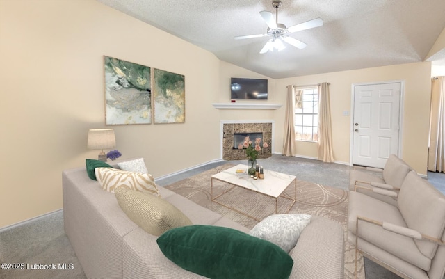 living room featuring ceiling fan, a textured ceiling, a tile fireplace, carpet floors, and lofted ceiling