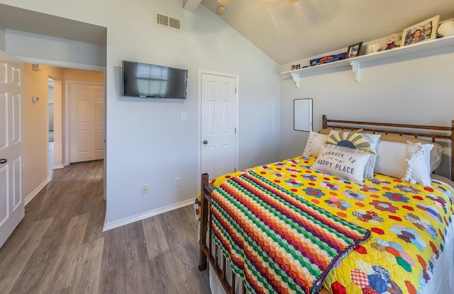 bedroom featuring baseboards, vaulted ceiling with beams, wood finished floors, and visible vents