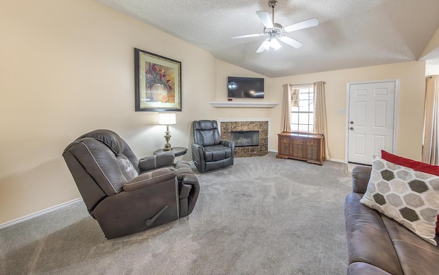 living area featuring ceiling fan, a textured ceiling, a tiled fireplace, vaulted ceiling, and carpet flooring