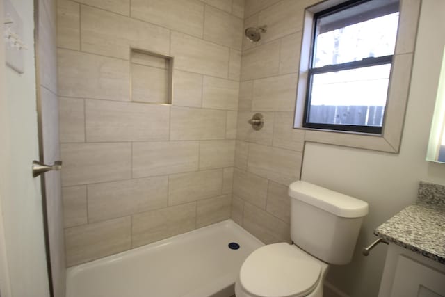 full bath featuring tiled shower, vanity, and toilet