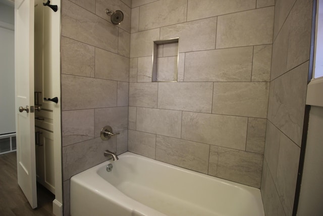 full bath with bathing tub / shower combination, wood finished floors, and visible vents